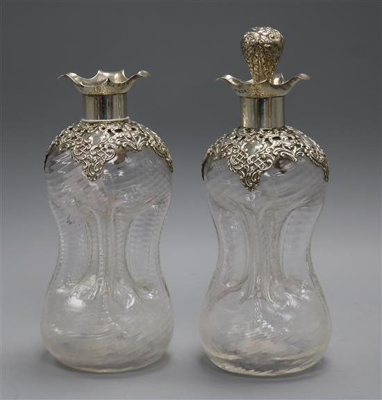 A pair of Edwardian repousse silver mounted glass waisted glug decanters and one stopper, 24.7cm with stopper.